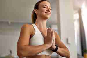 Foto gratuita vista ad angolo basso della donna atletica con le mani giunte che praticano yoga a casa