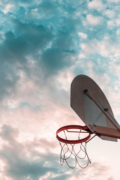 Vista di angolo basso del cerchio di pallacanestro contro il cielo nuvoloso