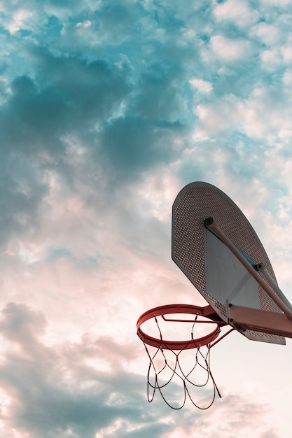 曇った空に対してバスケットボールフープの低い角度のビュー