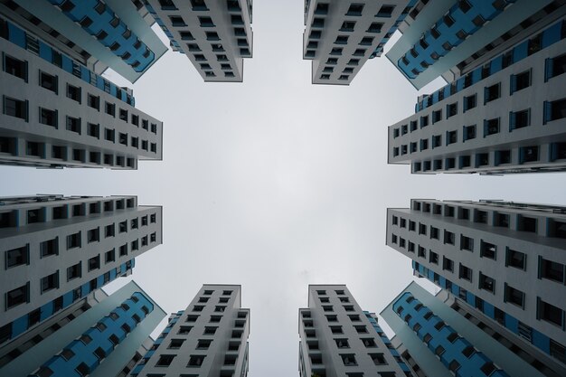 Low angle view of blue and white modern buildings under a cloudy sky