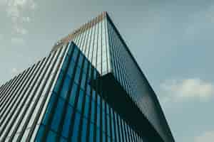 Free photo low angle view of a building in a glass facade under the beautiful cloudy sky