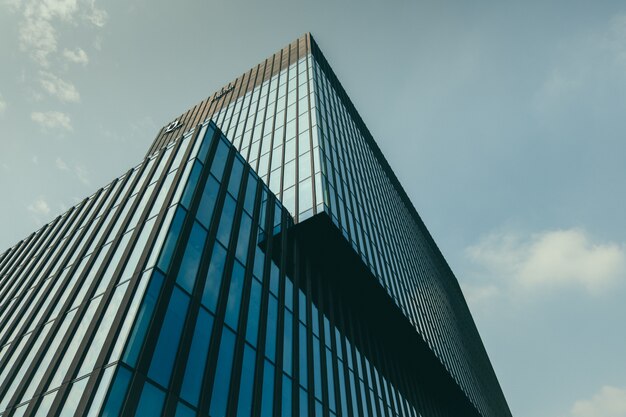 Low angle view of a building in a glass facade under the beautiful cloudy sky