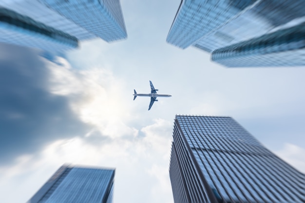 low angle view of business buildings with plane flying over
