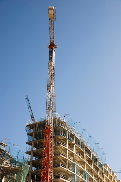 Foto gratuita vista di angolo basso della gru di costruzione vicino al sito contro cielo blu