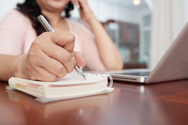 Low angle view of cropped blurred woman filling out her organizer