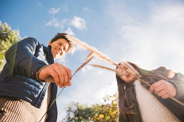 Free photo low angle view of a father and daughter holding reeds