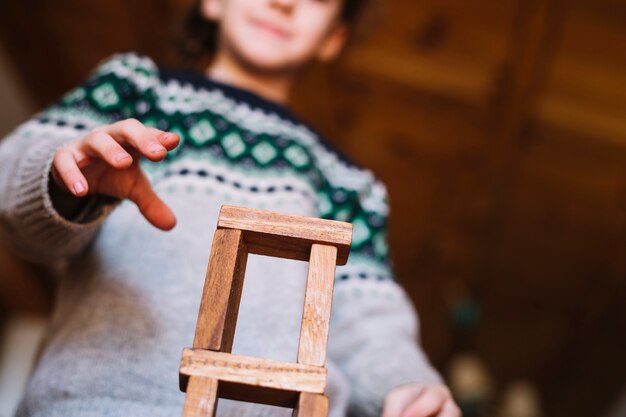 女の子の手の低い角度のビューは、積み上げられた木製ブロックで遊んでいる