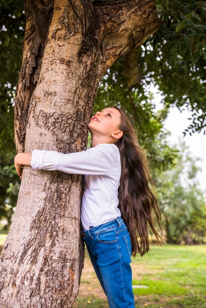 Low angle view of a girl with long hairs hugging tree