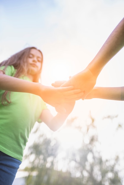 Free photo low angle view of girls stacking their hand in sunlight