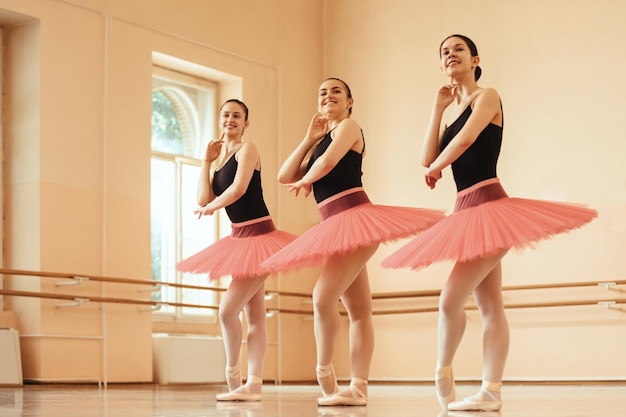 Free photo low angle view of happy ballerinas posing at ballet studio