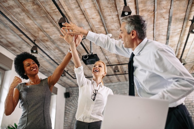 Low angle view of happy colleagues celebrating business success and having fun in the office