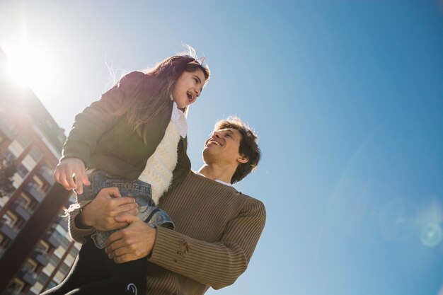 彼の娘を運ぶ幸せな父親の低い角度のビュー