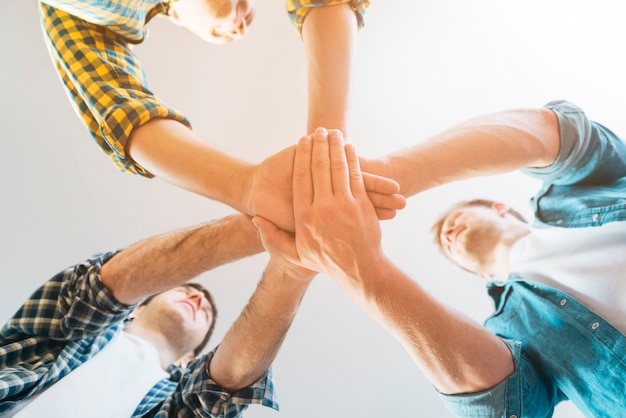 Free photo low angle view of male friends stacking hands against white background