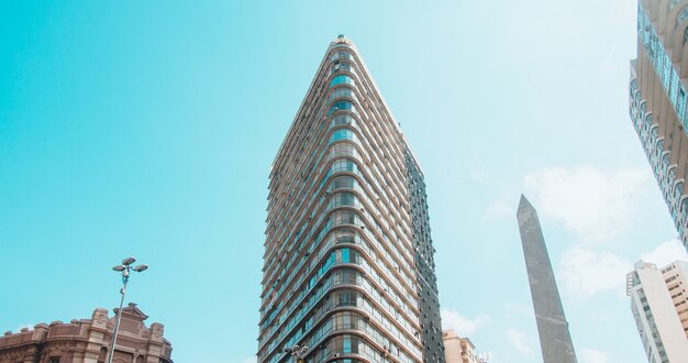 Low angle view of modern buildings under a blue sky and sunlight