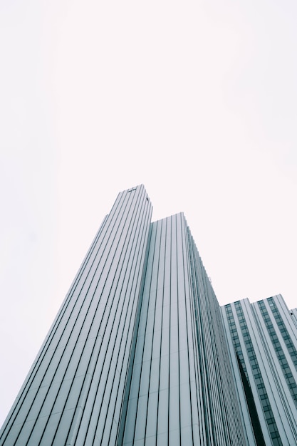 Low angle view of a modern skyscraper with blue and white windows under a white sky