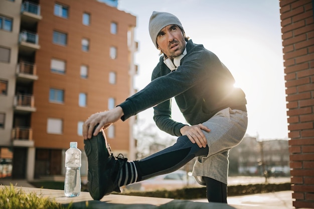 無料写真 屋外でのスポーツトレーニングの準備をしながら、男性アスリートがウォーミングアップして脚を伸ばしているローアングルビュー