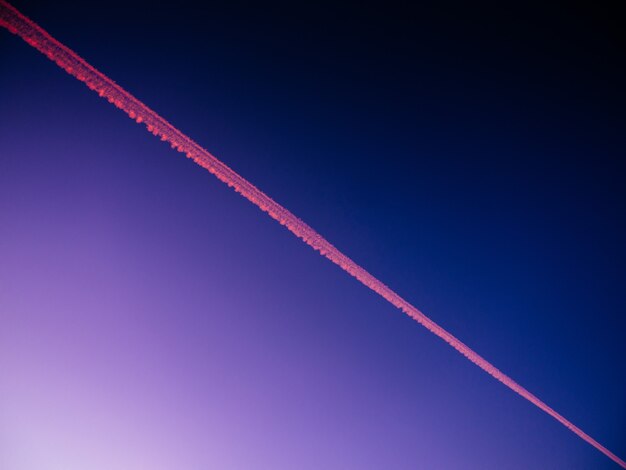夕方の青空にある飛行機の航跡のローアングル ビュー – 背景に最適
