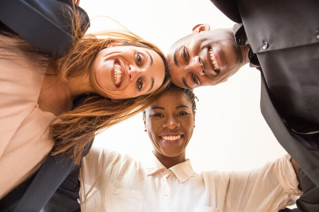 Low angle view of three embracing happy multiethnic colleagues