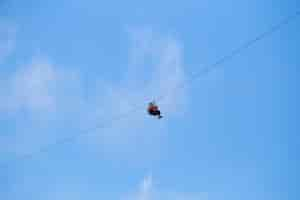 Free photo low angle view of tourist riding a zip line adventure against blue sky