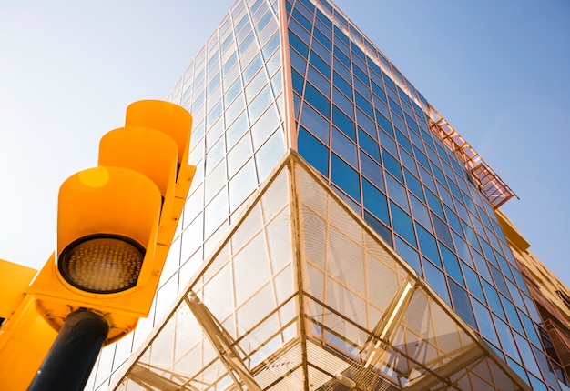 Free photo low angle view of traffic light near the modern corporate building against blue sky