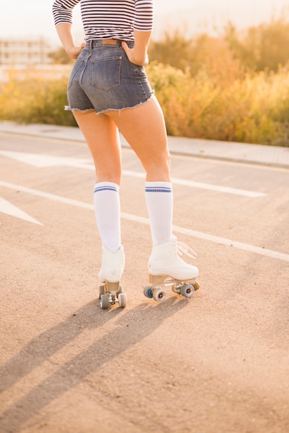 道路の上に立ってビンテージローラースケートを着て女性の足の低角度のビュー