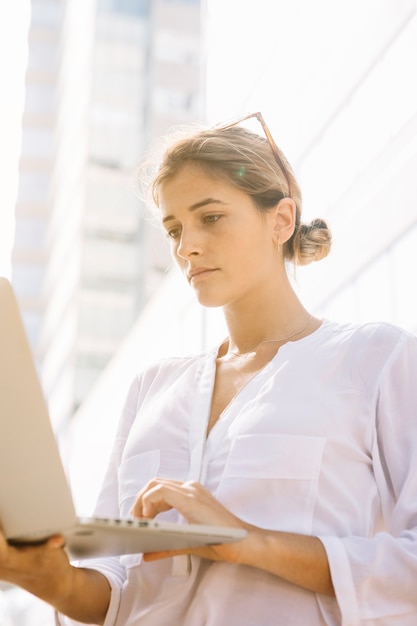 Low angle view of young businesswoman using laptop at outdoors