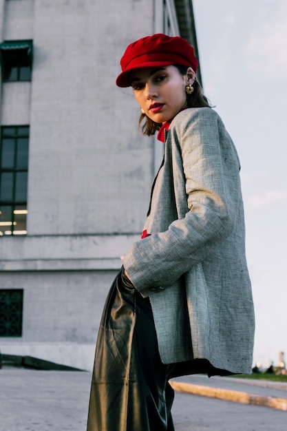 Free photo low angle view of young fashionable woman with her hands in pocket