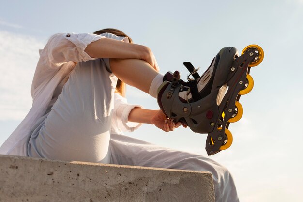 Free photo low angle of woman adjusting her roller blades