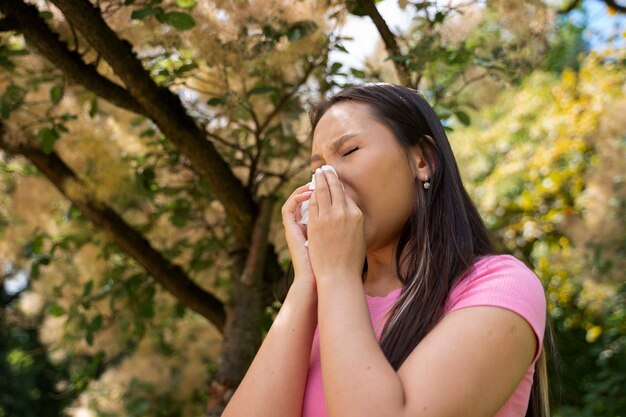 Low angle woman blowing her nose