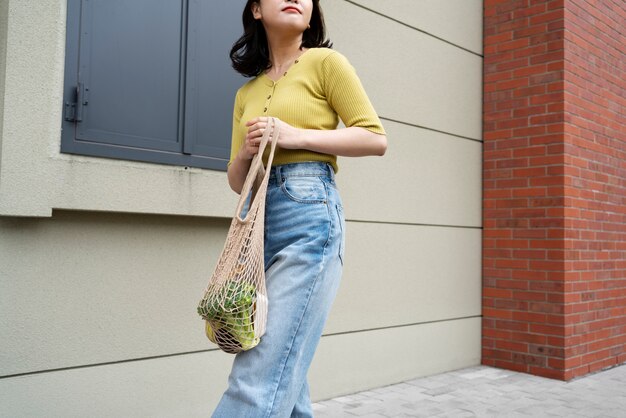Low angle woman carrying groceries in tote bag