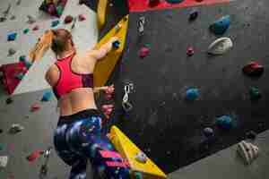 Free photo low angle woman climbing wall