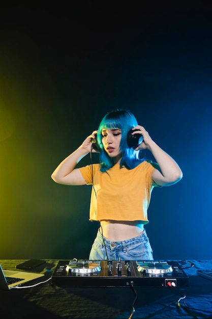 Low angle woman dj in club entertaining crowd
