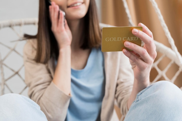 Free photo low angle of woman holding credit card and talking on the phone