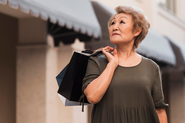 Foto gratuita sacchetti della spesa della tenuta della donna di angolo basso