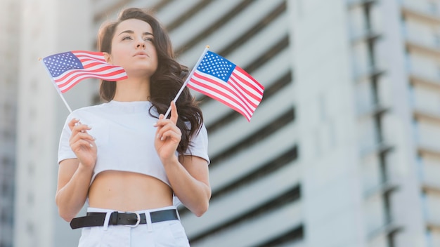 Женщина низкого угла держа флаги США