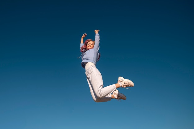 Free photo low angle woman jumping in nature