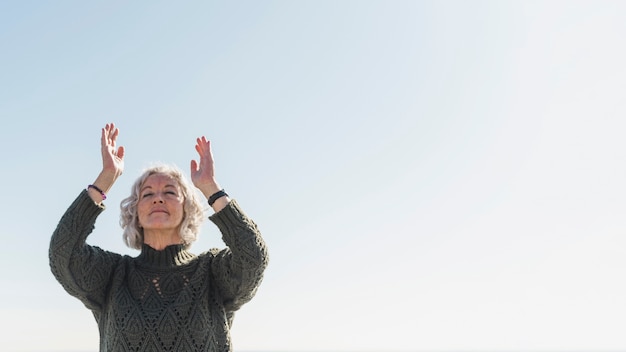 Free photo low angle woman meditating outdoors