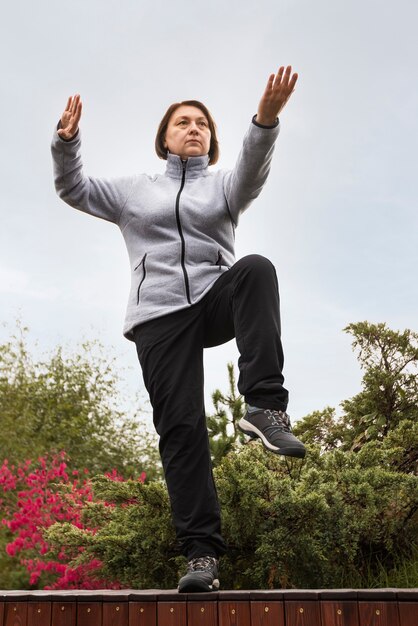 Donna di angolo basso che pratica il tai chi all'aperto