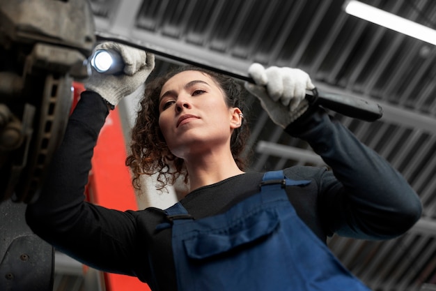 Free photo low angle woman repairing car