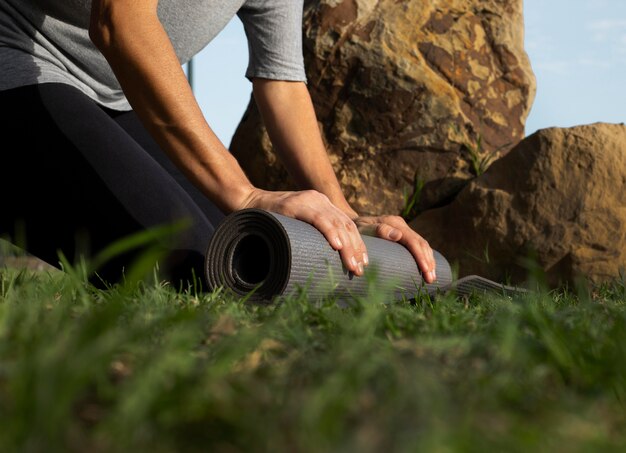 Низкий угол наклона коврика для йоги женщины на траве