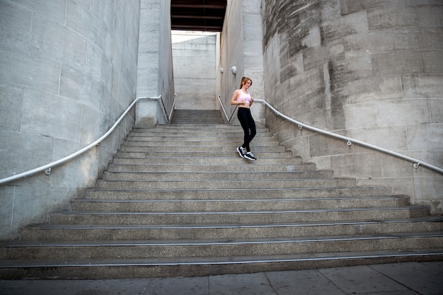 Free photo low angle woman running down stairs