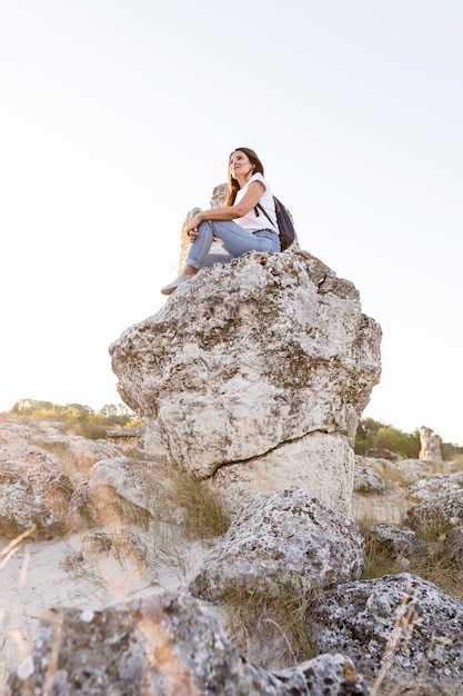 Low angle woman sitting on a rock