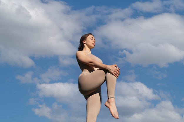 Low angle woman stretching on sunny day