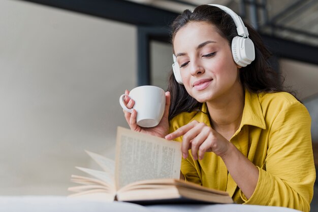 Low angle woman with cup and headphones