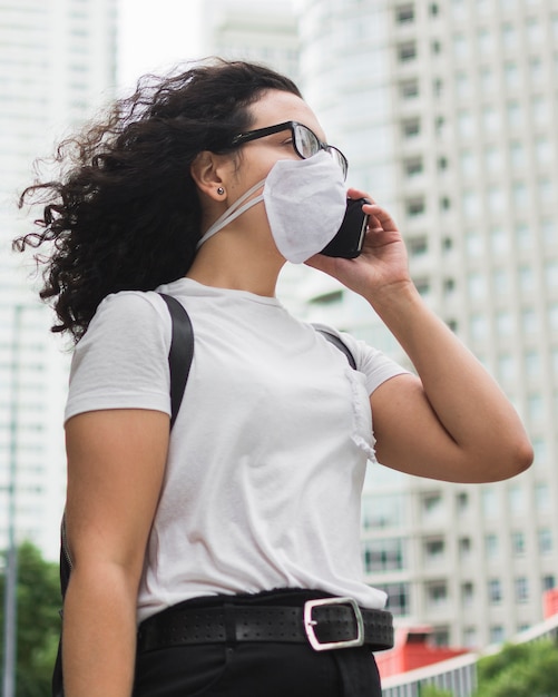 Low angle woman with medical mask talking on the phone