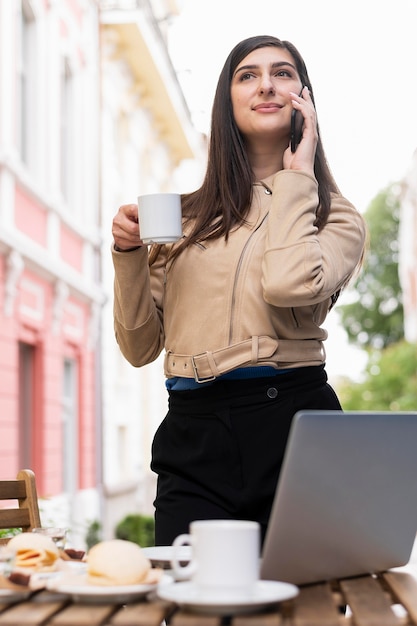 Free photo low angle of woman working and having lunch and coffee