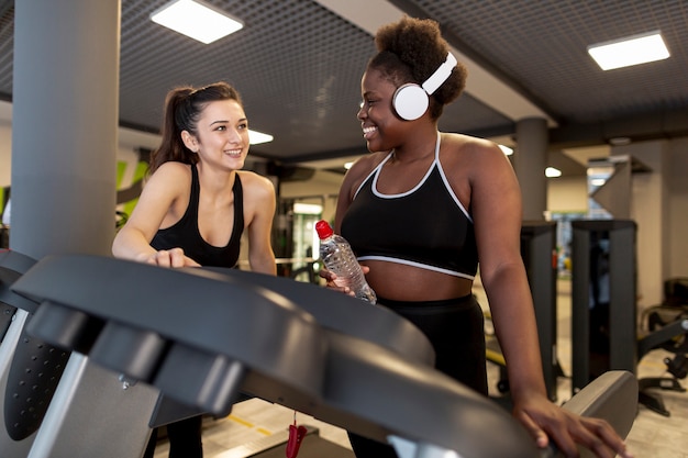 Foto gratuita donne di angolo basso in palestra sul tapis roulant