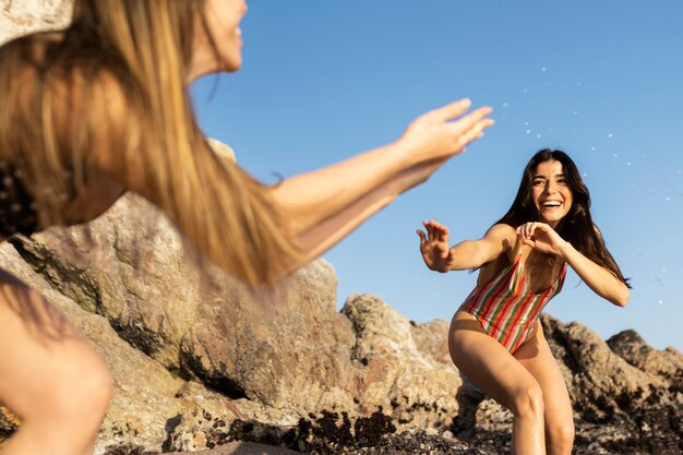 Low angle women playing around the sea