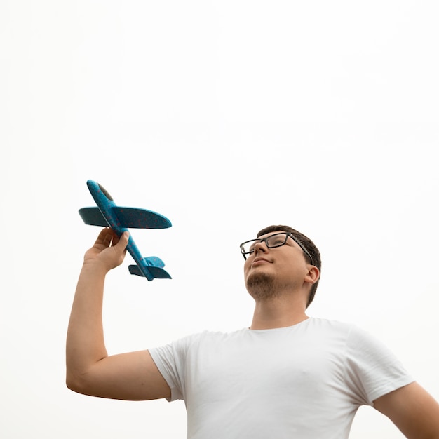 Free photo low angle of young man holding an airplane