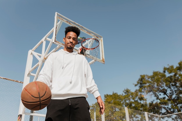 Free photo low angle young man playing basketball